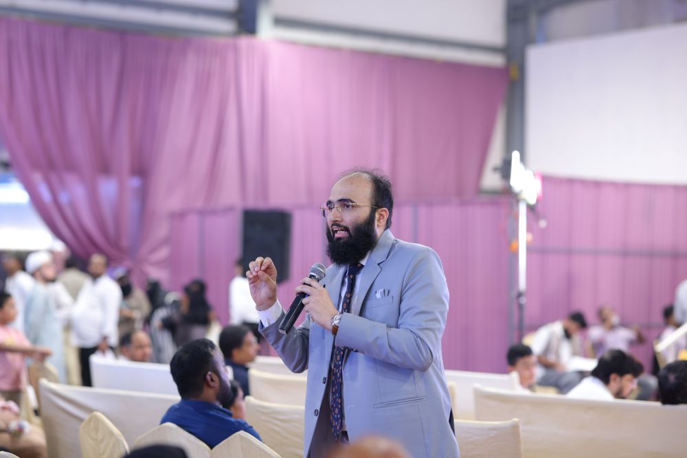 Dr. Khizer answering audience questions with a microphone